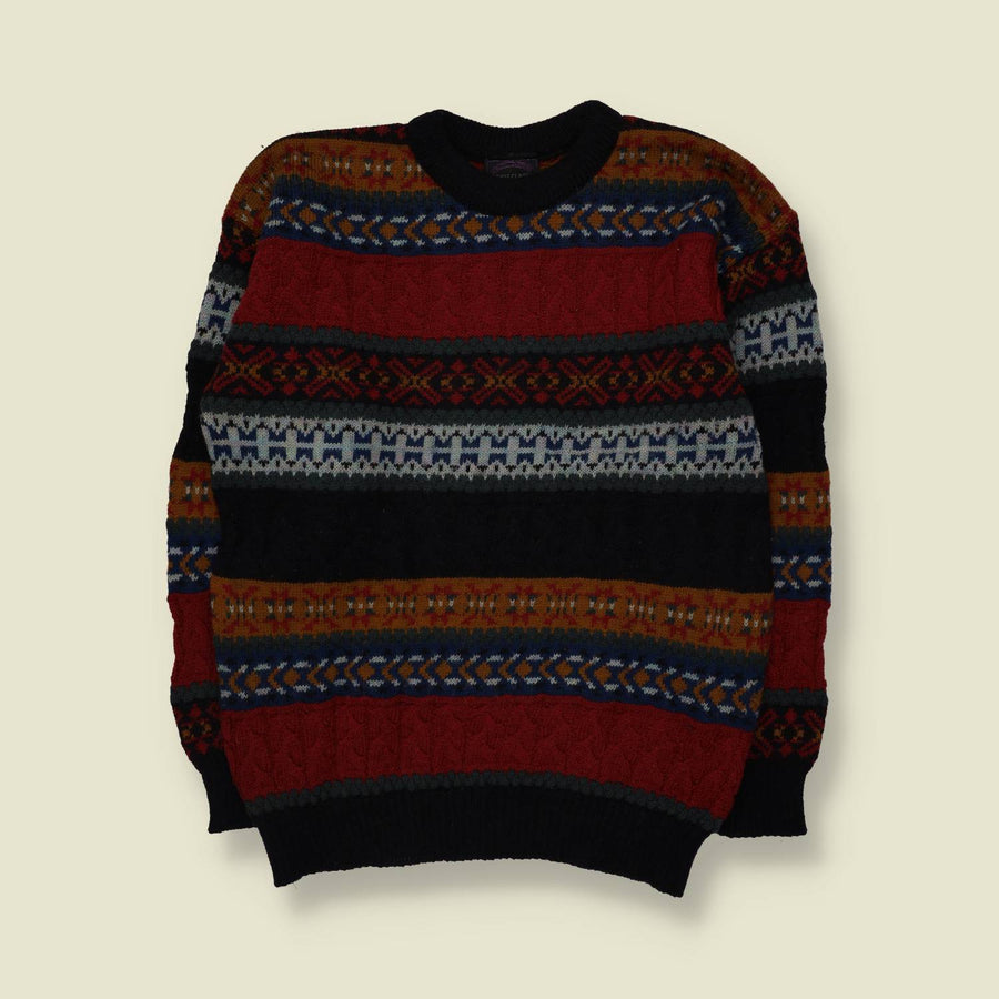 A long-sleeve crewneck knit sweater with horizontal Fair Isle style patterns in red, black, navy blue, rust orange, and cream, laid flat against a light beige background.